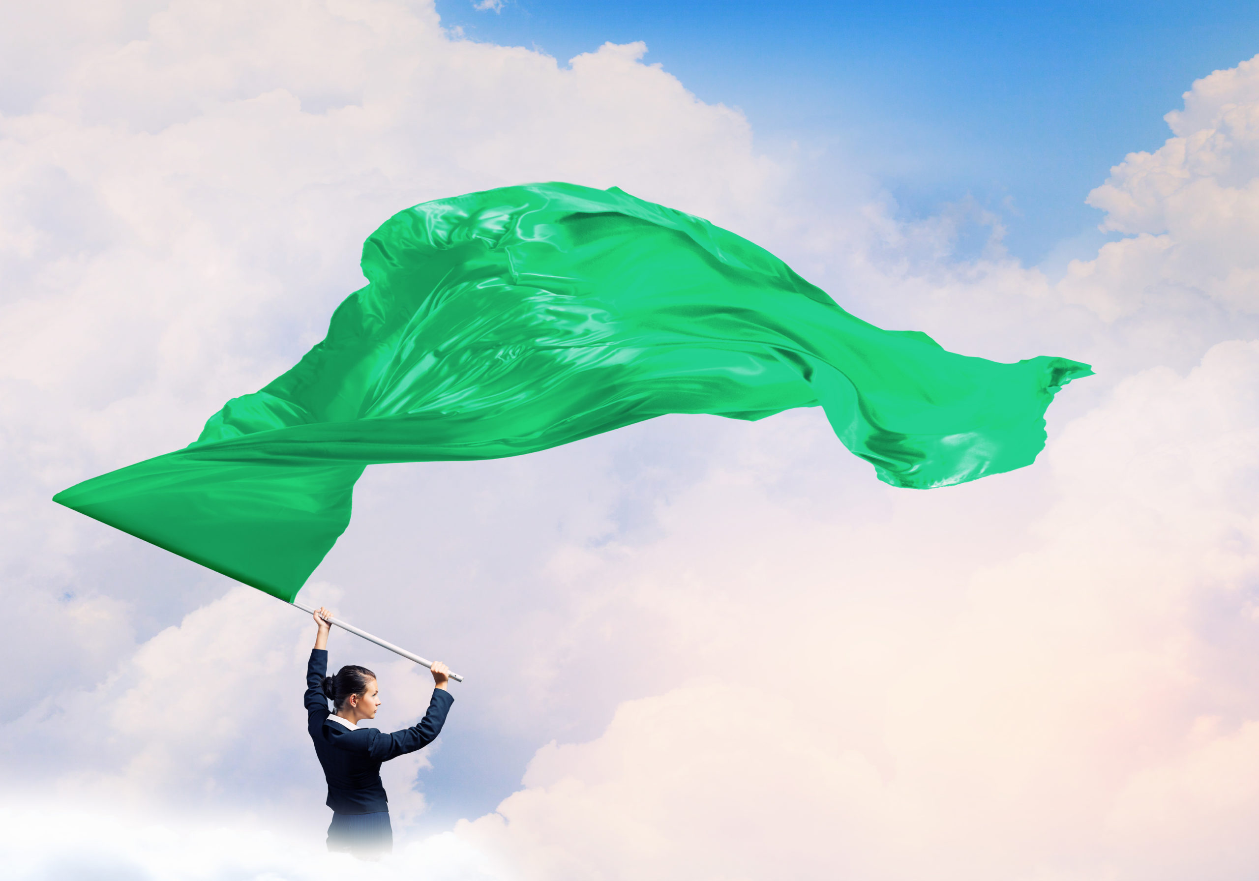 Белый флаг на зеленом фоне. Женщина машет флагом. Размахивает флагом. Зеленый флаг гонки. Зеленое Знамя любви.