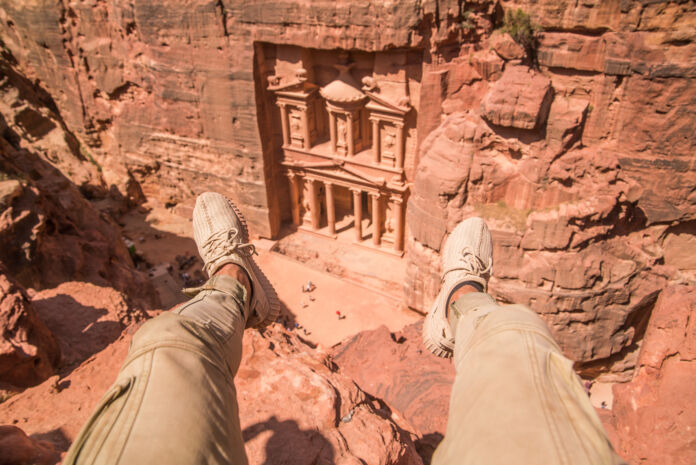 traveler overlooking petra from cliffs