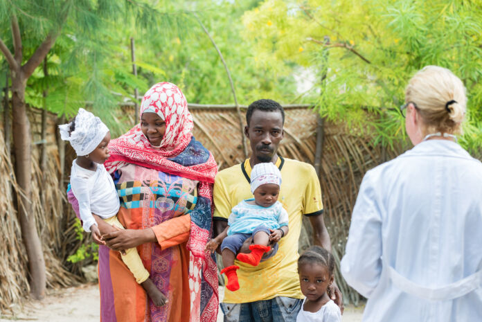 Caucasian woman doctor with African black family outdoors Vaccini contro malattie infettive