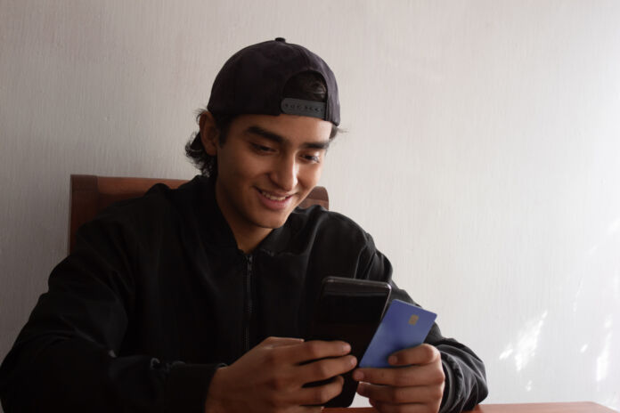 smiling and excited young man making an online purchase with his Paghetta