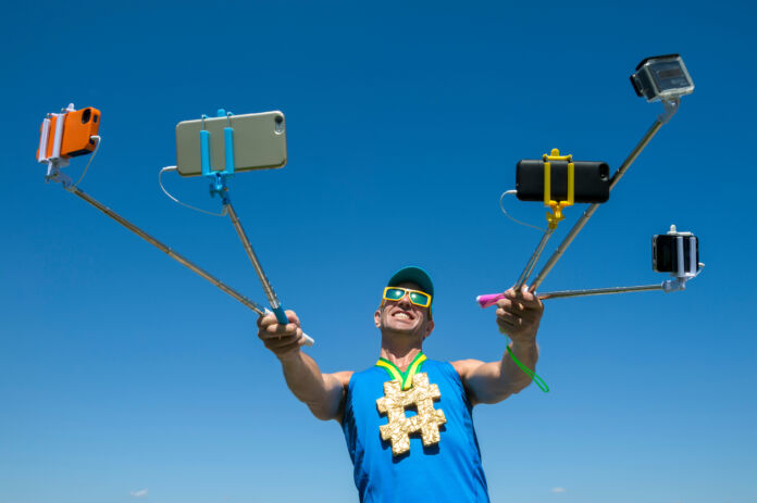 Hashtag gold medal athlete smiling for his many gadgets on selfi