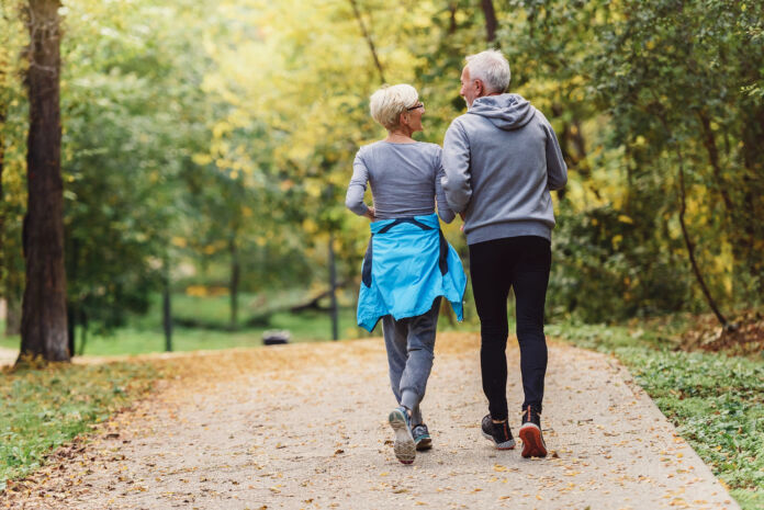 Cheerful active senior couple jogging in the park. Exercise toge